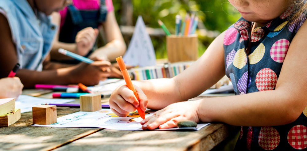 Children coloring and drawing at an outdoor table